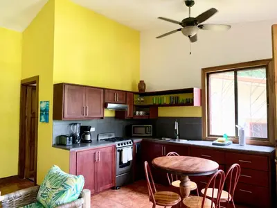 a kitchen with wooden cabinets and a table with chairs at Cozy AC EcoCondo 4 with Pool Wildlife Visits in Quepos