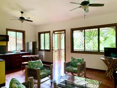 a living room with chairs and a table and windows at Cozy AC EcoCondo 4 with Pool Wildlife Visits in Quepos