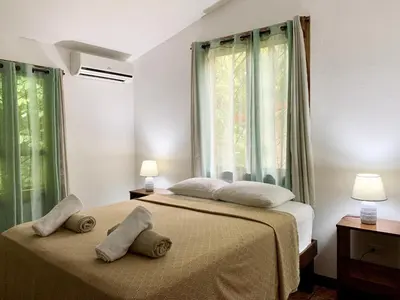 a bedroom with two beds and two windows at Cozy AC EcoCondo 4 with Pool Wildlife Visits in Quepos