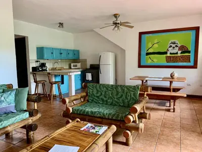 a living room with couches and a kitchen at EcoCondo 5 in Secured Community Paradise w pool in Quepos