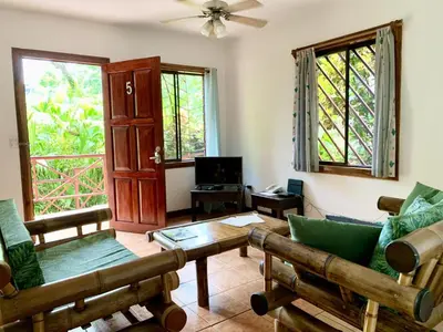 a living room with a couch and chairs and windows at EcoCondo 5 in Secured Community Paradise w pool in Quepos
