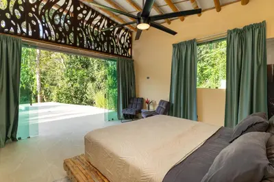 a bedroom with a bed and a large window at Brand New Villa Bambú with large pool near MA in Quepos