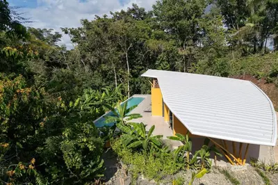a house with a white roof and trees at Brand New Villa Bambú with large pool near MA in Quepos