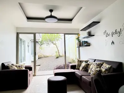 a living room with a couch and a sliding glass door at Casa Matiza, 7 min SJO airport, free parking, AC in Santiago Este