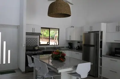 a kitchen with a refrigerator and a table with chairs at Casa Mari Black Stallion in Tamarindo