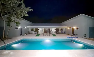 a swimming pool in front of a house at night at Casa Mari Black Stallion in Tamarindo