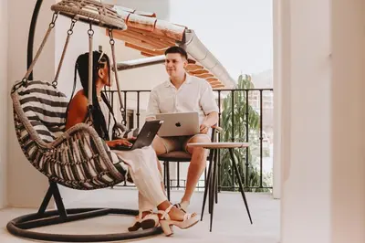 a man and a woman sitting in a chair with a laptop at El Prado: New 2br Condo in Las Catalinas in Playa Danta