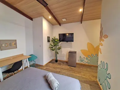 a bedroom with a bed and a desk and a tv at Jungla Urbana, BnB Adult Only in Pavas