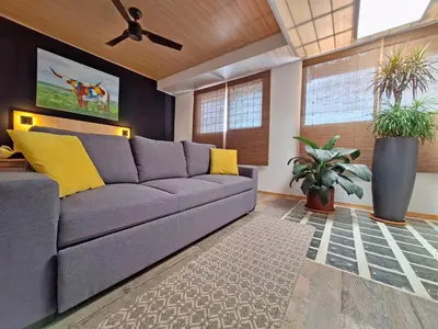 a living room with a gray couch and yellow pillows at Jungla Urbana, BnB Adult Only in Pavas