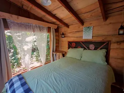 a bedroom with a bed in a log cabin at Tipi Bribri in Heredia