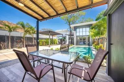 a patio with a glass table and chairs and a swimming pool at Casa Encanto Potrero, Flamingo in Liberia