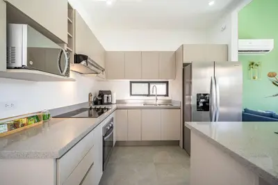 a kitchen with white cabinets and a stainless steel refrigerator at Casa Encanto Potrero, Flamingo in Liberia