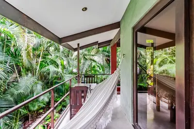 a hammock on the balcony of a house with trees at VIP La Lora Beach Villa best family home in Santa Teresa Beach