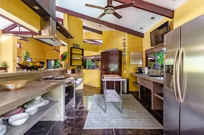 a kitchen with yellow walls and a stainless steel refrigerator at VIP La Lora Beach Villa best family home in Santa Teresa Beach