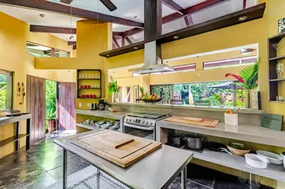a kitchen with yellow walls and stainless steel appliances at VIP La Lora Beach Villa best family home in Santa Teresa Beach