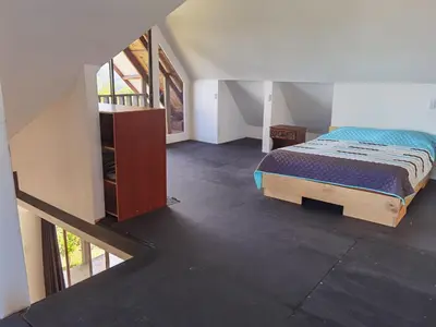 a bedroom with a bed and a staircase in a room at Casa Roble Cabaña romántica en la montaña de Costa Rica in San Cristóbal Sur