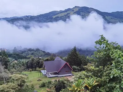 a house on a hill in the mountains with clouds at Casa Roble Cabaña romántica en la montaña de Costa Rica in San Cristóbal Sur