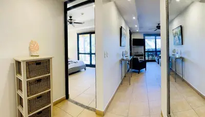 a hallway with a mirror and a room with a bed at Direct Beach & Pool Access l 247 Security in Jacó