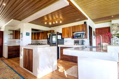 a large kitchen with wooden cabinets and a counter top at Ocean and Jungle views! AC, Wi-Fi, kitchen in Manzanillo