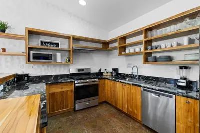 a kitchen with wooden cabinets and stainless steel appliances at Modern Home with Chic Bohemian Style and Zen Outdoor Oasis with Swimming Pool and Tiki Style Dining Space in Potrero