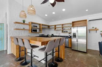 a kitchen with a wooden table and bar stools at Modern Home with Chic Bohemian Style and Zen Outdoor Oasis with Swimming Pool and Tiki Style Dining Space in Potrero