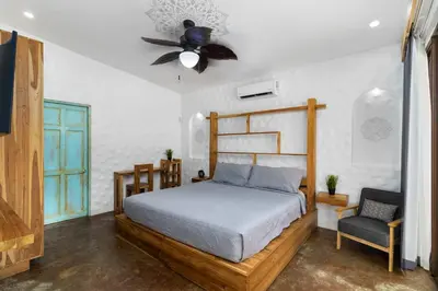 a bedroom with a bed and a fan and a chair at Modern Home with Chic Bohemian Style and Zen Outdoor Oasis with Swimming Pool and Tiki Style Dining Space in Potrero
