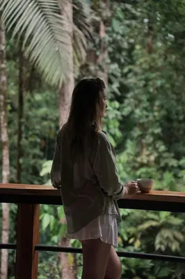a woman standing on a balcony with a bowl in her hand at Fauna Lodge in Drake