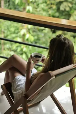 a woman sitting in a chair holding a cup of coffee at Fauna Lodge in Drake