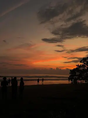 a group of people standing on a beach at sunset at Cabañas MOHE’S Uvita in Uvita