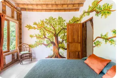 a bedroom with a tree mural on the wall at Casa BAMBÚ, enjoy nature in San Juan de Mata