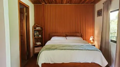 a bedroom with a large bed with a wooden wall at Grand Luna - Monteverde in Tilarán