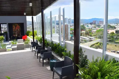 a balcony with chairs and a view of a city at Apartamento con piscina y espacio de trabajo in San José