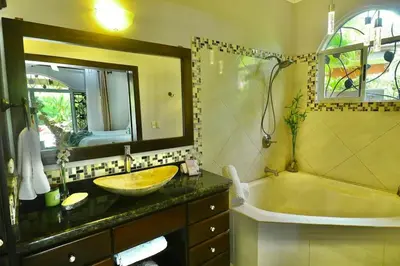 a bathroom with a sink and a tub and a mirror at Villa Encantada by Vacation Pura Vida in Esterillos