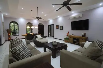 a living room with couches and a flat screen tv at Villa Encantada by Vacation Pura Vida in Esterillos