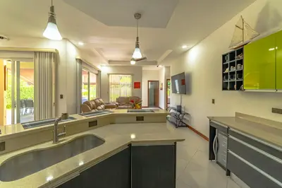 a large kitchen with a sink and a living room at Villa Jardin by Vacation Pura Vida in Esterillos