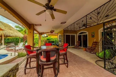 a patio with a table and chairs and a pool at Villa Felicidad by Vacation Pura Vida in Esterillos