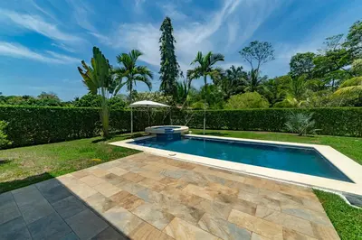 a swimming pool in a garden with an umbrella at Villa Arrecife by Vacation Pura Vida in Bejuco