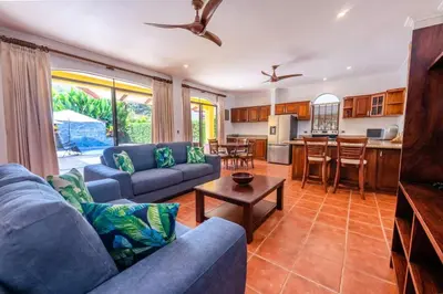 a living room with blue couches and a kitchen at Villa Escapadita by Vacation Pura Vida in Esterillos