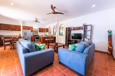 a living room with two blue chairs and a kitchen at Villa Escapadita by Vacation Pura Vida in Esterillos
