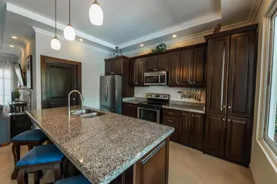 a kitchen with wooden cabinets and a granite counter top at Casa 40 Villa Mario by Vacation Pura Vida in Bejuco