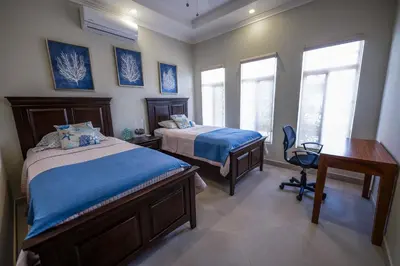 a bedroom with two beds and a desk and two windows at Casa 40 Villa Mario by Vacation Pura Vida in Bejuco
