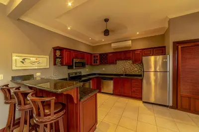 a kitchen with red cabinets and a stainless steel refrigerator at Villa Estrella de Mar by Vacation Pura Vida in Bejuco