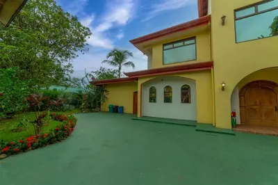a large yellow house with a driveway at Villa Macaw by Vacation Pura Vida in Esterillos Este
