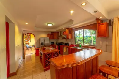 a kitchen with wooden cabinets and a counter top at Villa Macaw by Vacation Pura Vida in Esterillos Este