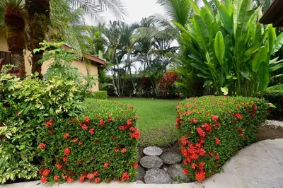 a garden with red flowers and plants at Villa Sendero by VacationPuraVida in Bejuco