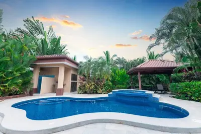 a swimming pool in front of a house with trees at Villa Sendero by VacationPuraVida in Bejuco