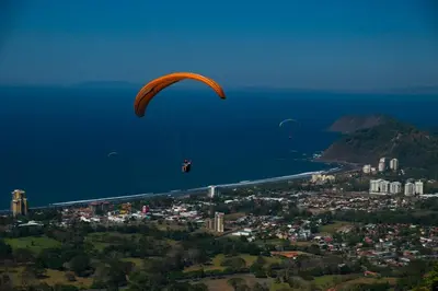 a person in a parachute flying over the water at Modern 2 Bed 2 Bath l Strong Wifi Carport in Jacó
