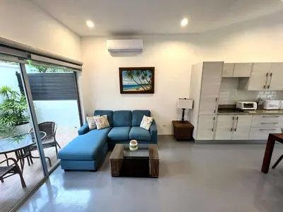 a living room with a blue couch and a kitchen at Carport Strong Wifi Vaulted Ceilings in Jacó