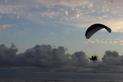 a person is riding a parachute over the ocean at The Wavefront Beachfront Condo in Bejuco in Bejuco