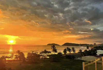 a sunset over the ocean with palm trees at Ocean Views l Steps to Beach l Sunset 305 in Jacó